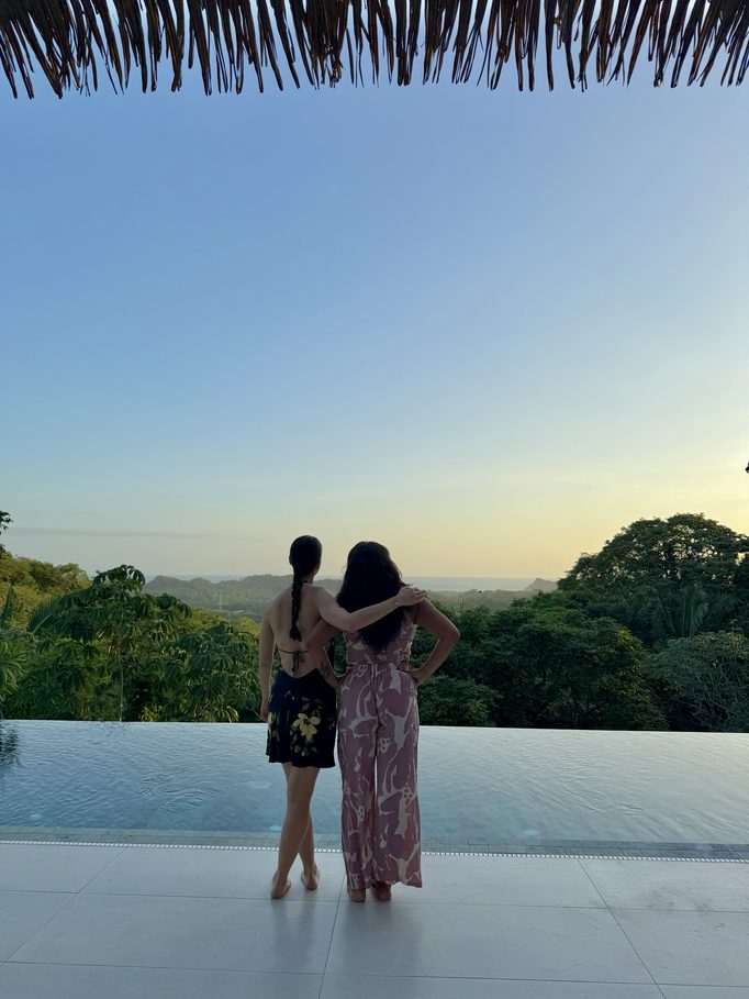 two women watching the sunset from the pool